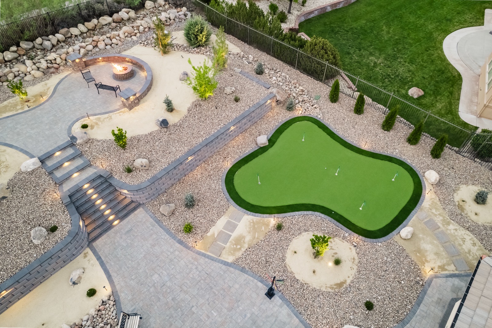 Backyard artificial turf putting green with cups and a fire pit patio in Reno