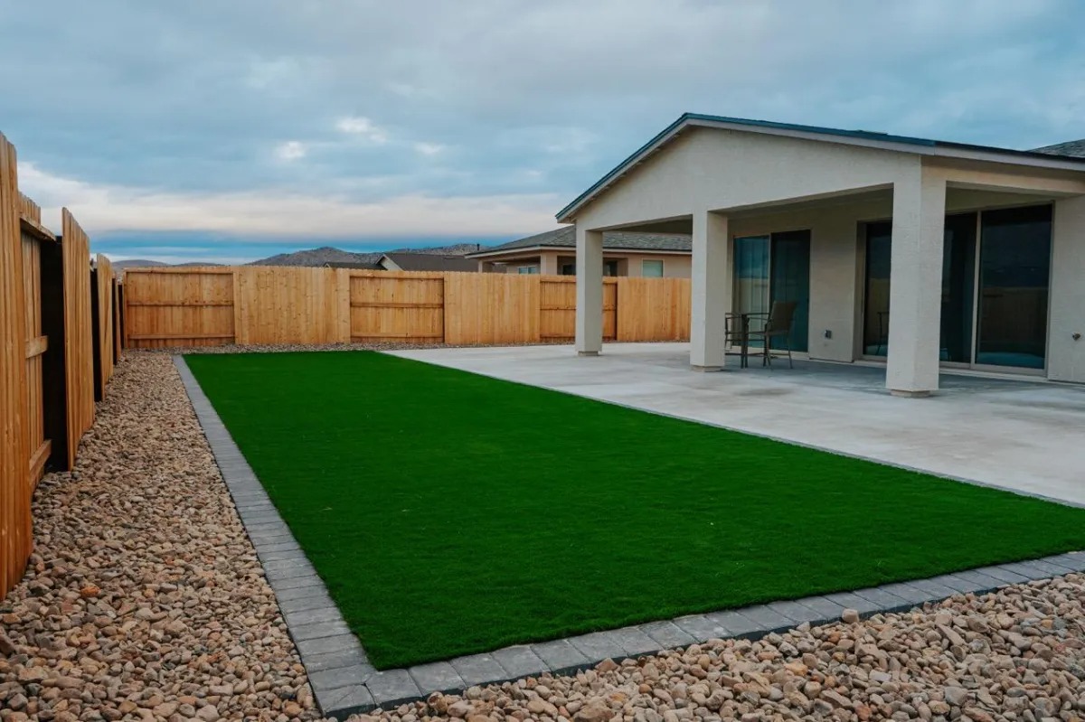 Artificial turf lawn set inside a paver border behind a Reno home